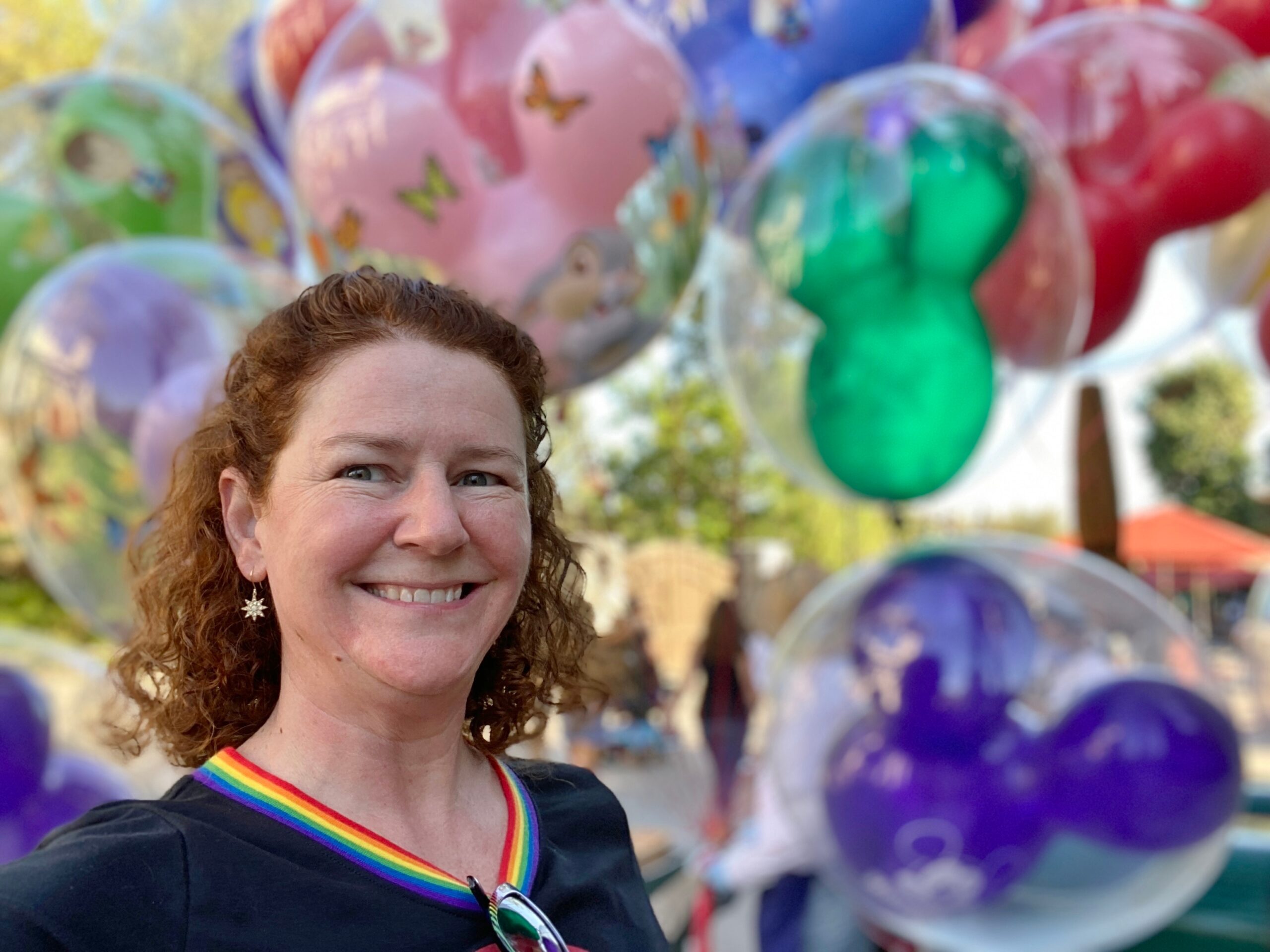 woman standing in front of Mickey Mouse-shaped balloons