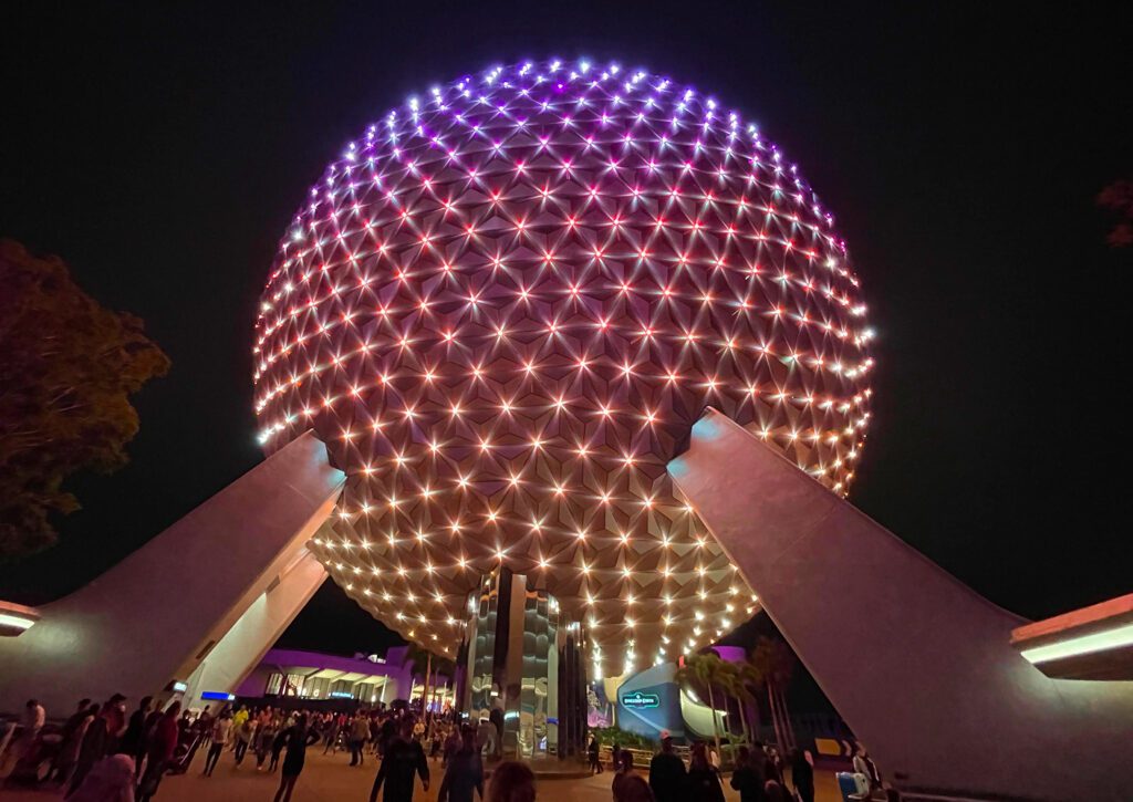 Spaceship Earth illuminated in purple and warm light at EPCOT after dark