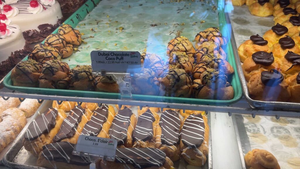 Dubai chocolate coco puffs and chocolate eclairs displayed inside the pastry case at Liliha Bakery.
