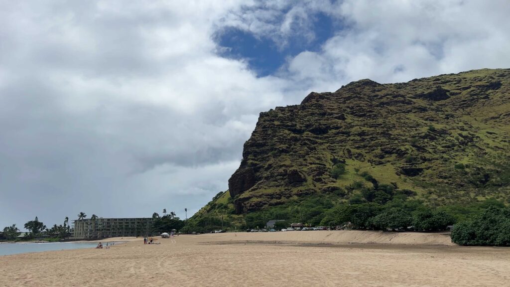 Wide sandy beach below steep green mountains at Makaha on the leeward coast of Oahu.