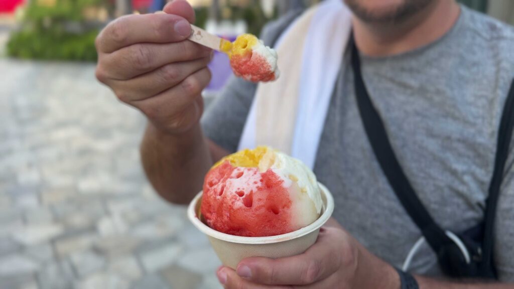 Person holding a bowl of red, yellow, and white shave ice from Ululani's in Kailua.