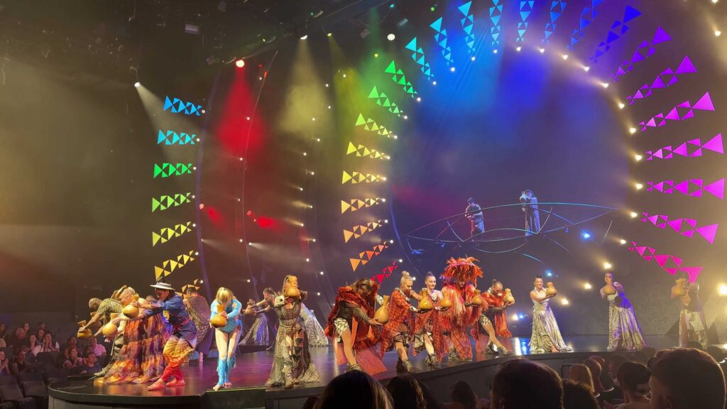 Cast of Auana by Cirque du Soleil performing beneath colorful stage lights in Waikiki.