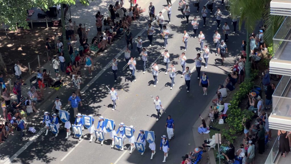 Marching band and cheer squad traveling through Waikiki during the King Kamehameha Celebration Floral Parade.