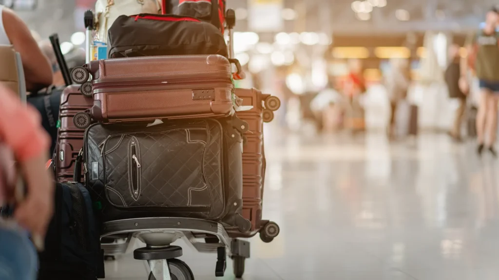 Suitcases stacked on a luggage trolley inside an airport terminal.