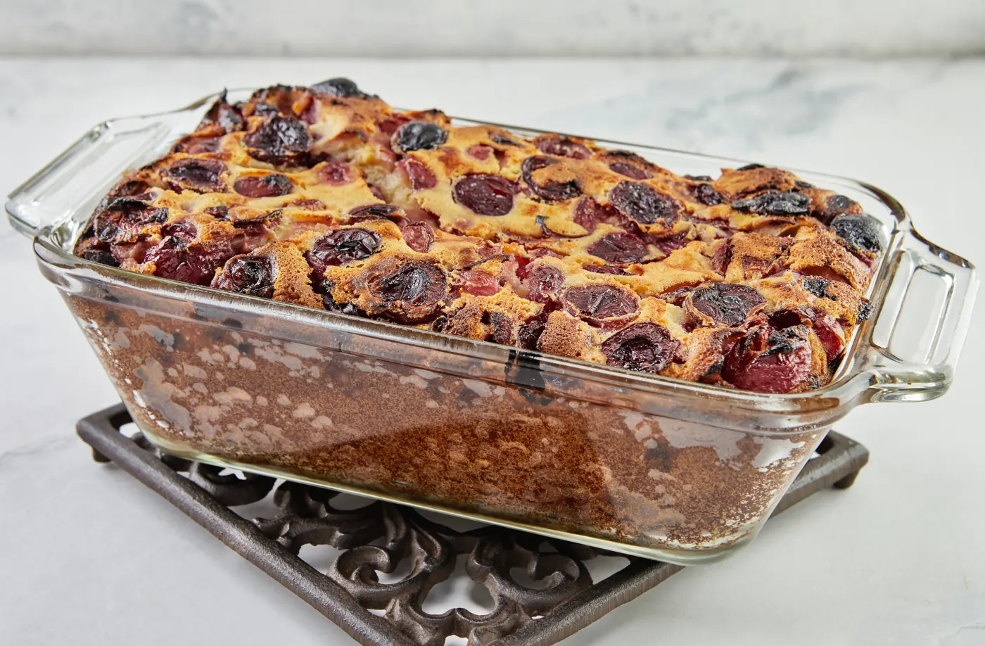 Cherry dessert baked in a clear rectangular glass dish resting on a trivet