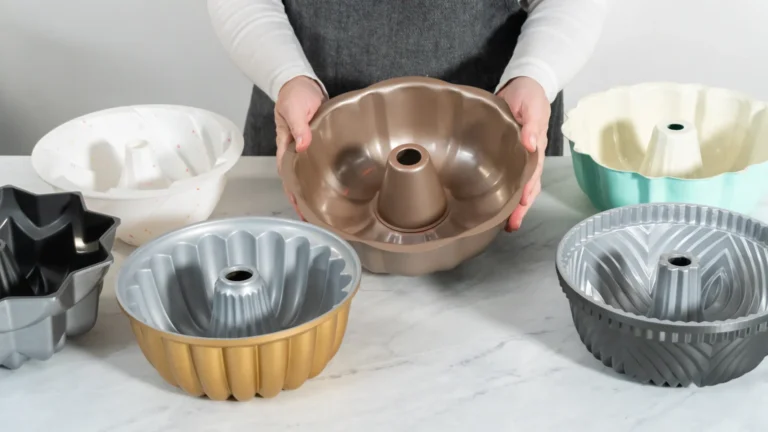 A baker holding a fluted cake pan among several differently shaped baking pans
