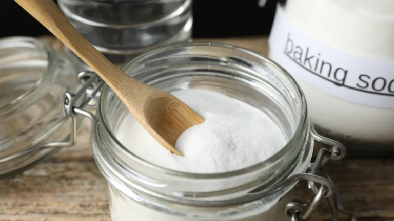 A wooden spoon rests in a glass jar of white powder beside a container labeled baking soda.