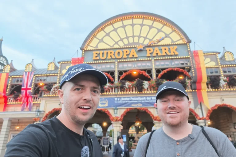 Beau and Sean in front of the illuminated Europa-Park entrance and its large park sign.