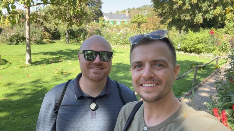 Beau and Sean smiling in Monet’s flower garden, with the house behind them.