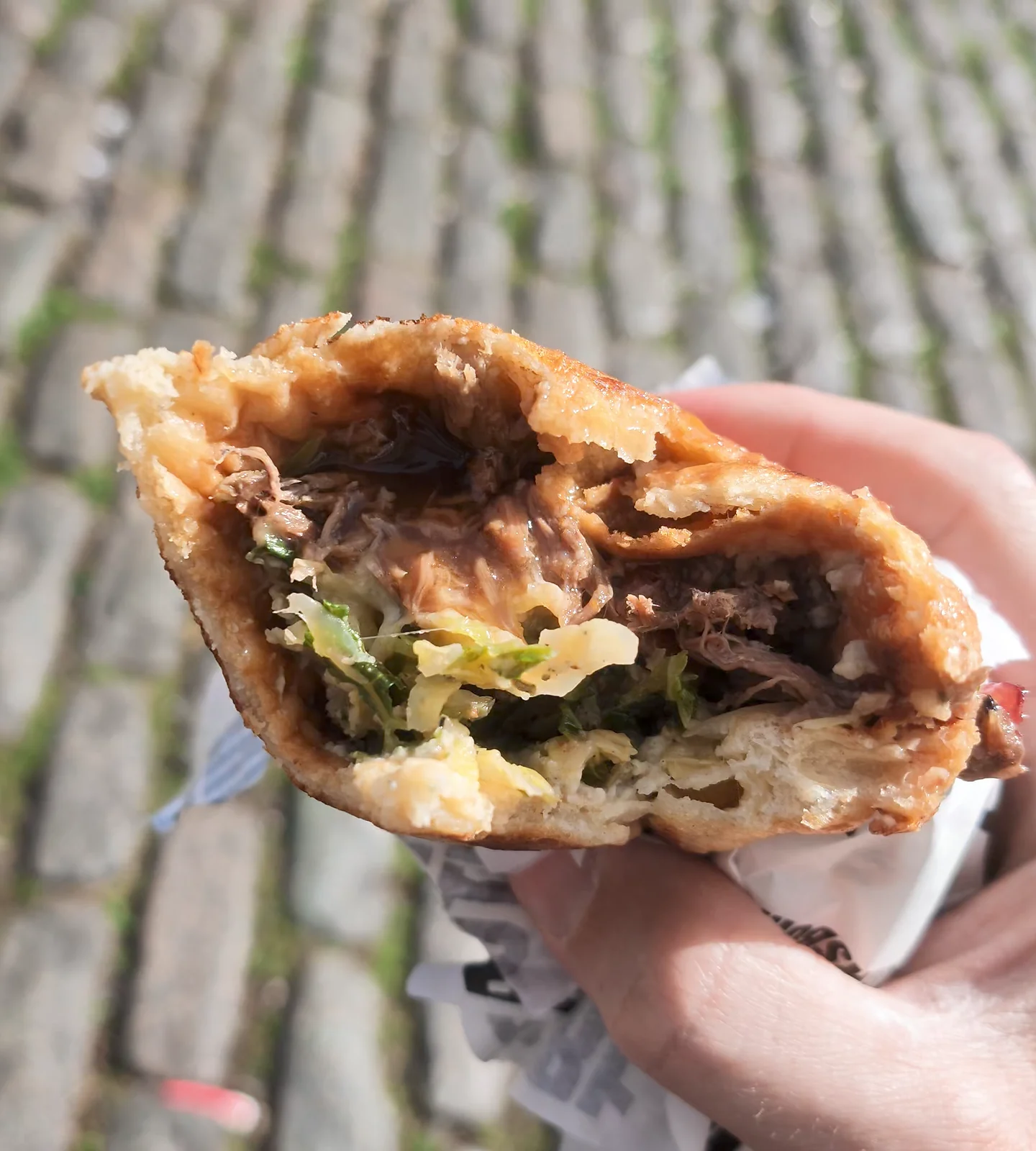 A hand holds a beef Yorkshire Burrito, with its filling visible, at Camden Market in London.