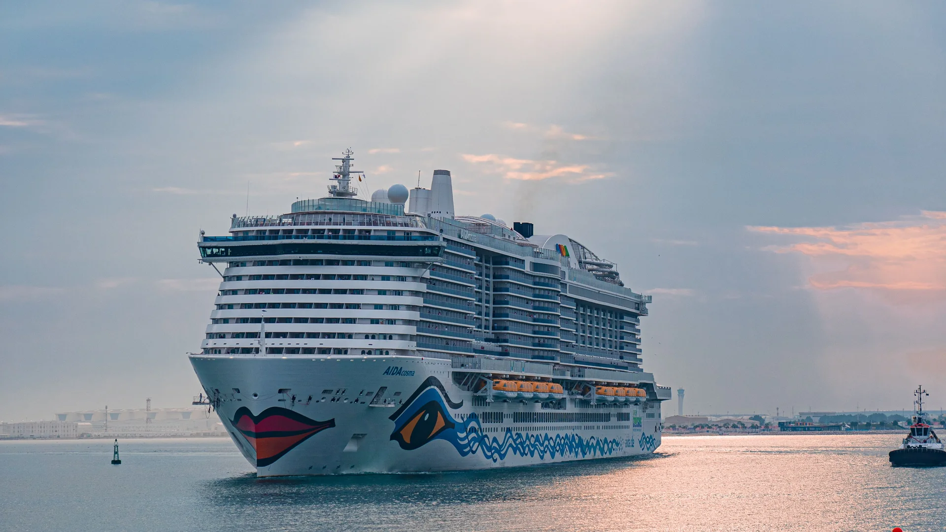 A cruise ship sits on calm water beneath a softly lit evening sky.