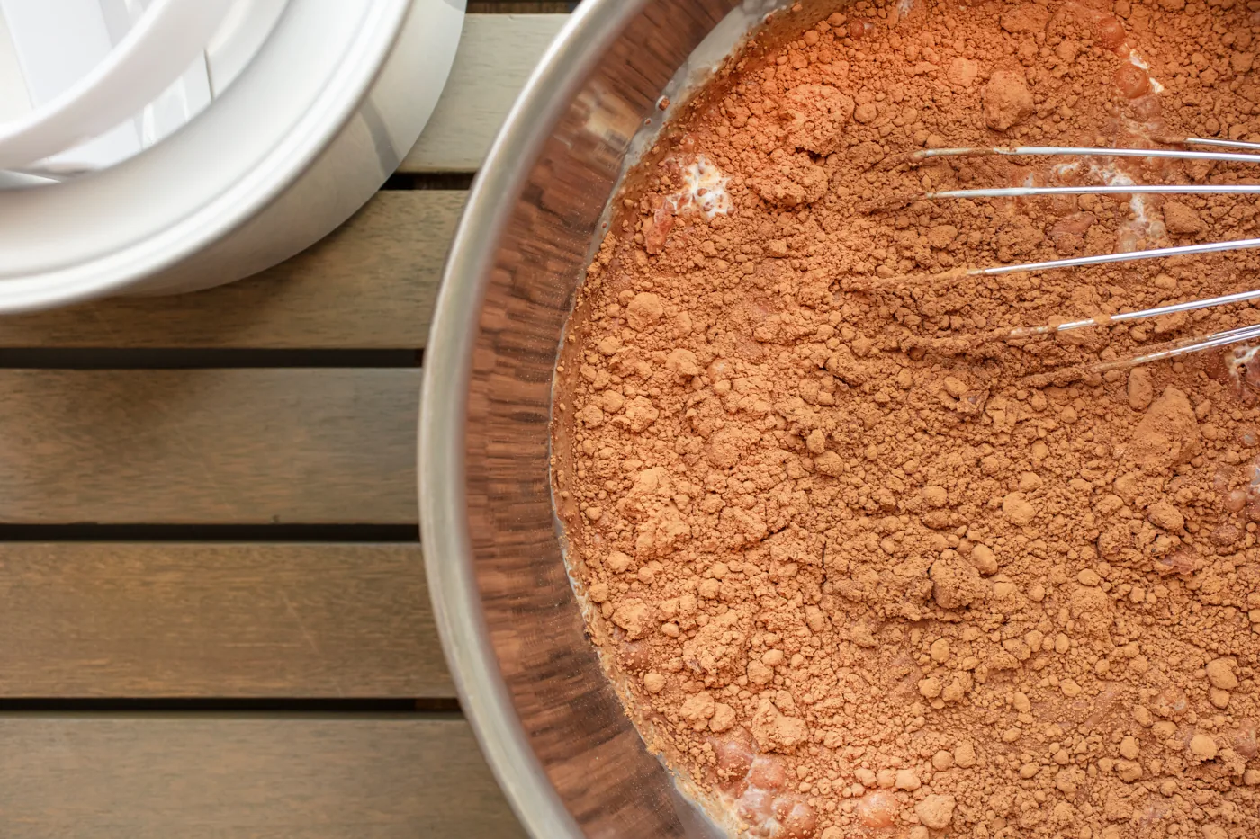 Cocoa powder and other dry baking ingredients in a metal bowl with a whisk.
