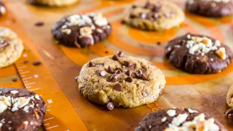 Chocolate chip and chocolate cookies resting on an orange baking mat with printed circles