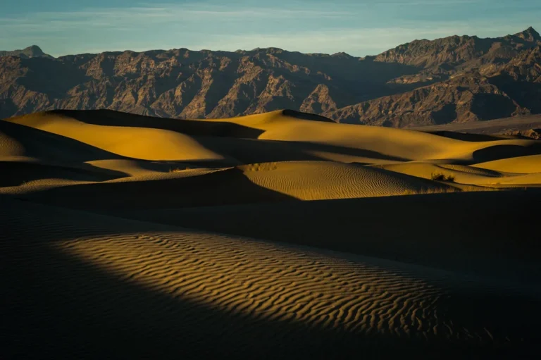 Wind-shaped sand dunes and distant mountains at Mesquite Flat in Death Valley.