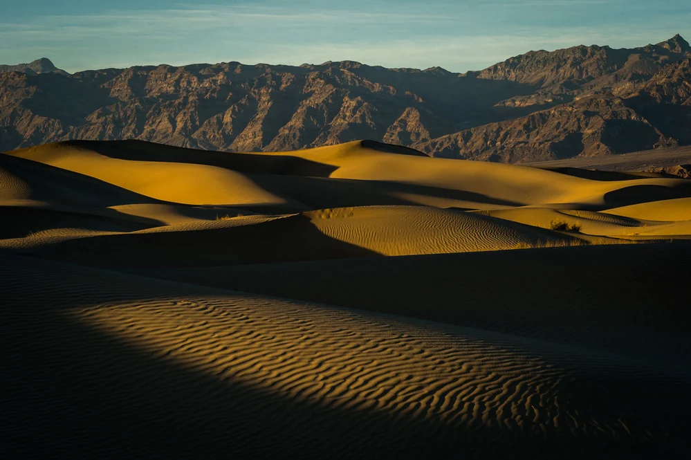 Wind-shaped sand dunes and distant mountains at Mesquite Flat in Death Valley.