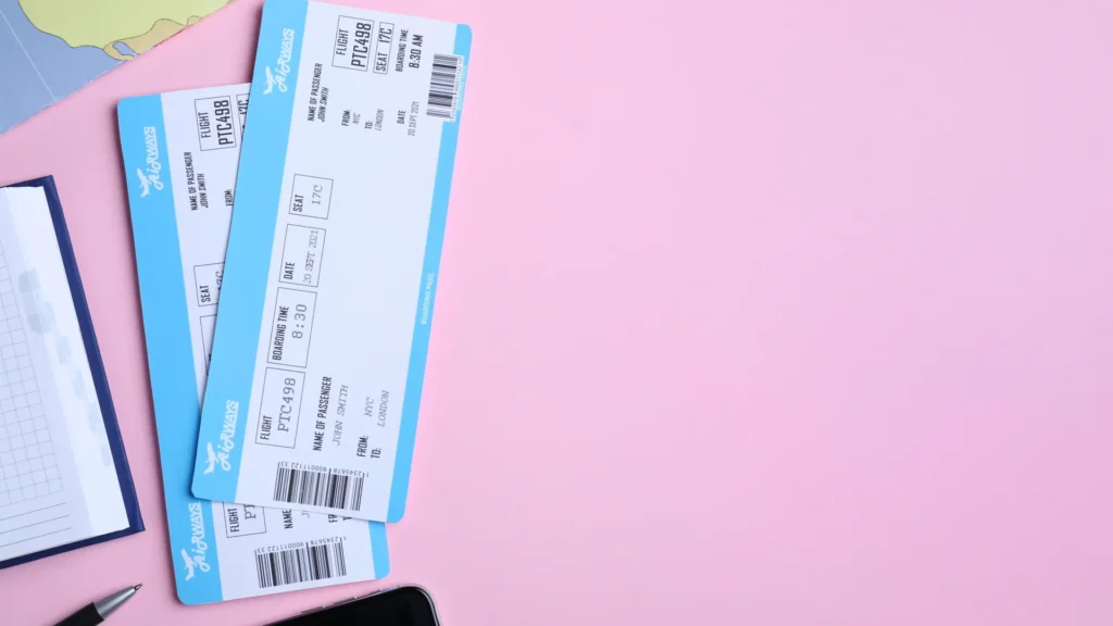 Travel tickets, a planner, and a smartphone arranged on a pink surface.