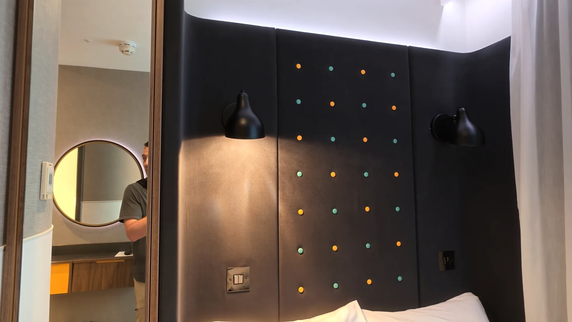 The bed, wall panel, and bathroom entrance in our Point A Paddington room.