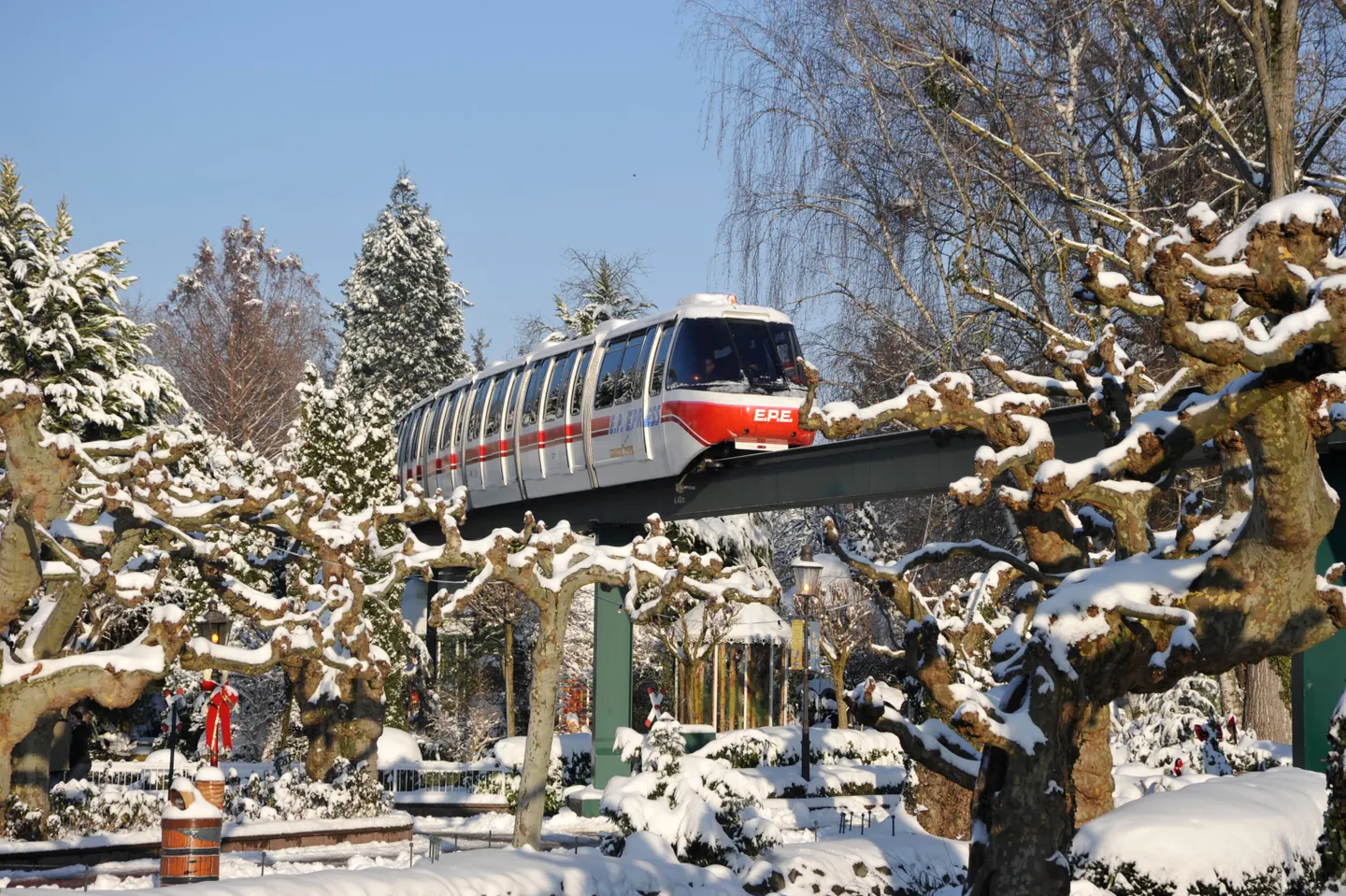 An EP Express monorail train passing snow-covered trees inside Europa-Park.