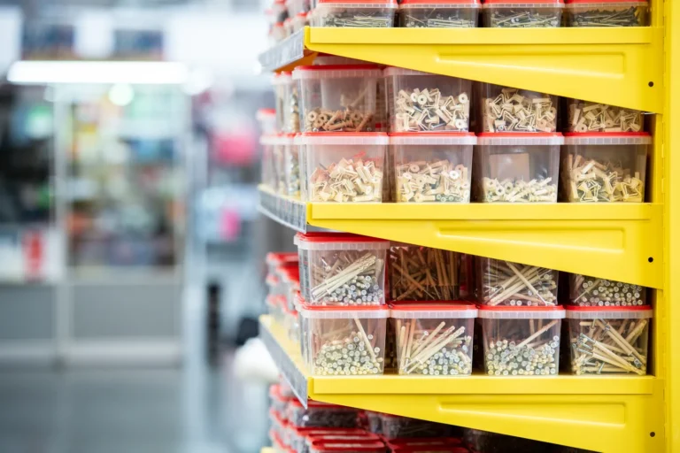 Clear bins of screws and bolts arranged on bright yellow hardware-store shelves.