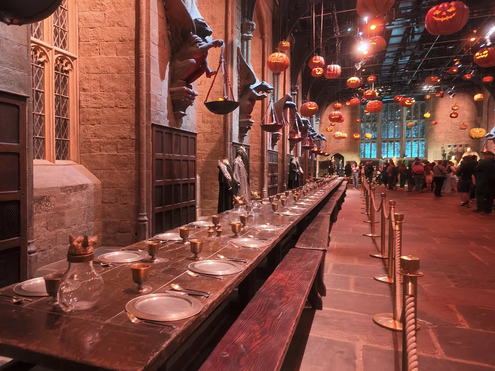 A long dining table leads through the Great Hall beneath hanging pumpkins at Harry Potter Studio Tour London.