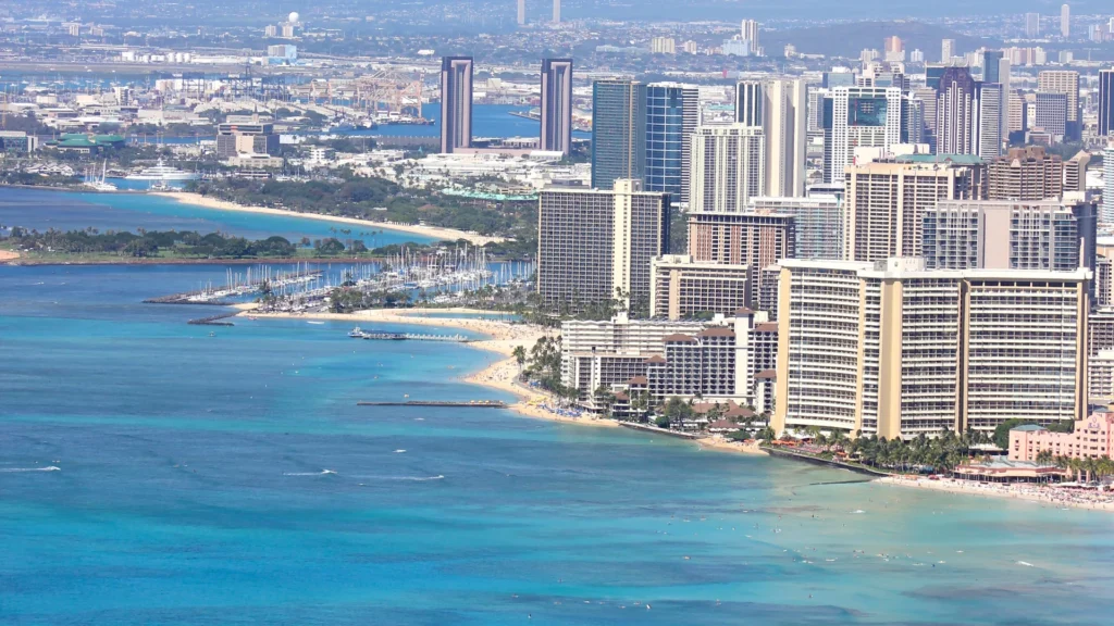 Waikiki Beach, Honolulu buildings, and green hills beneath a bright sky.