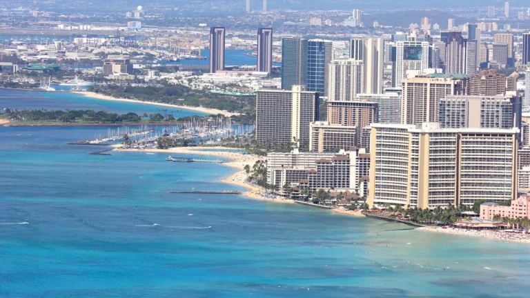 Waikiki Beach, Honolulu buildings, and green hills beneath a bright sky.