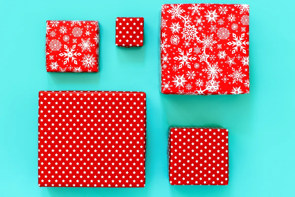 Red and white patterned gift boxes arranged on a turquoise background.
