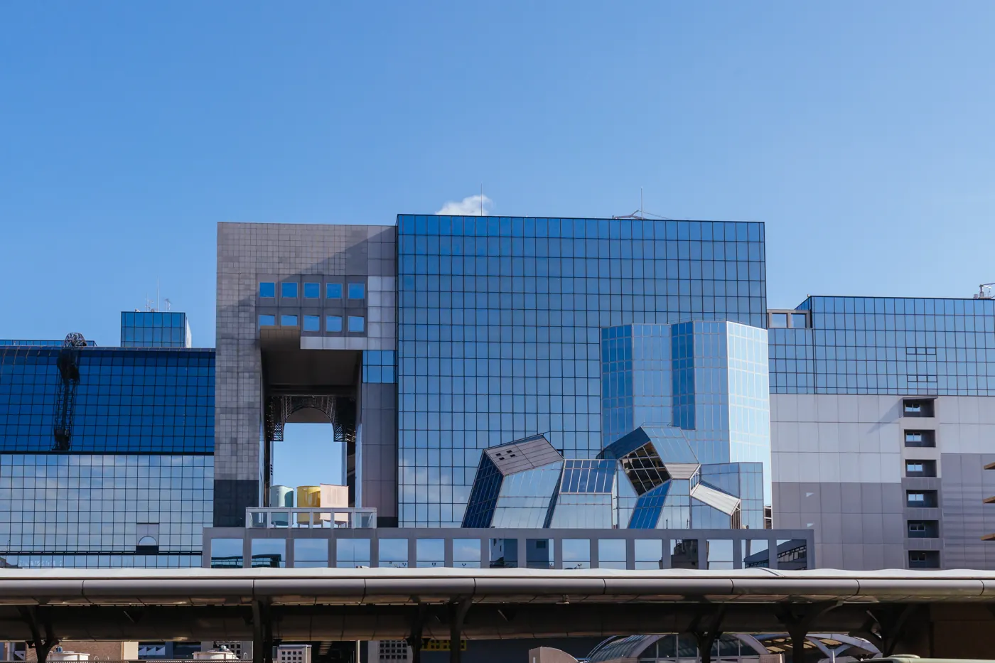 Blue glass and angular steel facade of Kyoto Station beneath a clear sky