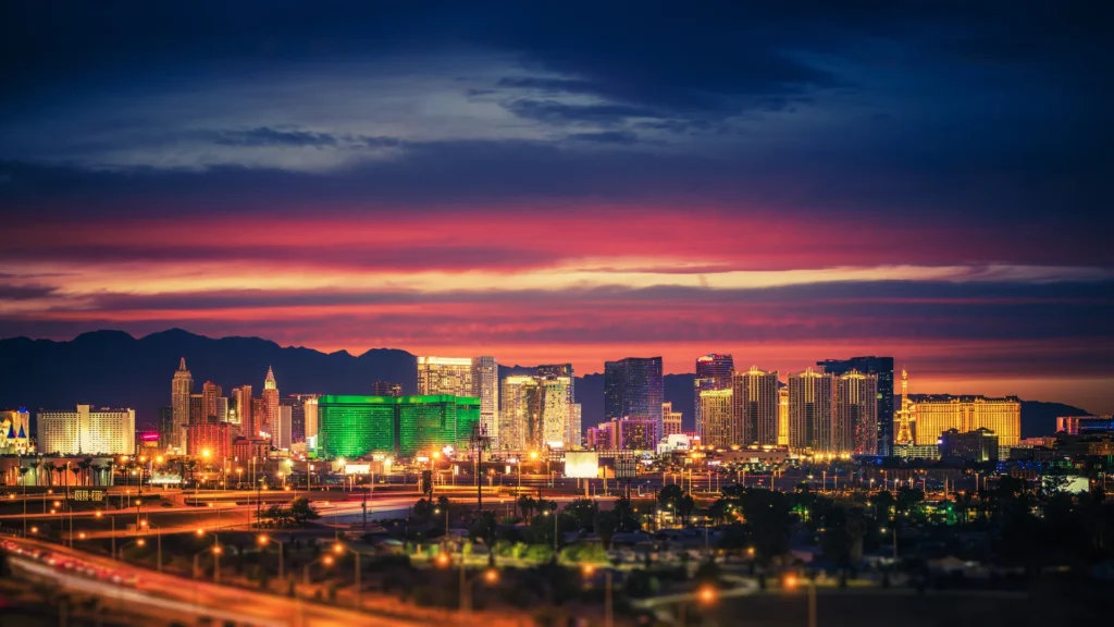 Illuminated Las Vegas Strip resorts beneath a purple and orange evening sky