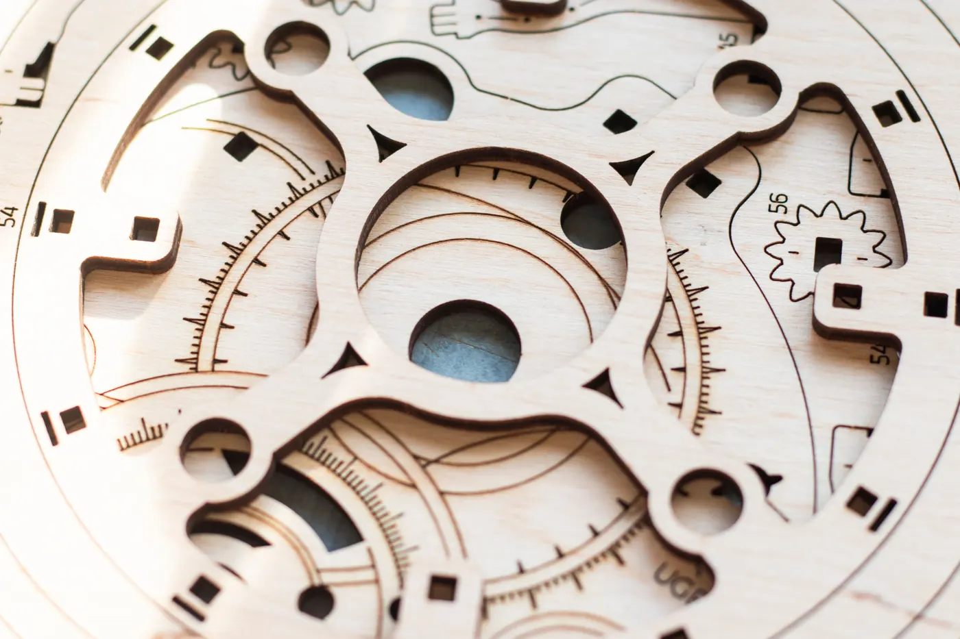 Overlapping light wooden components have cut openings, outlines, fine markings, and part numbers.
