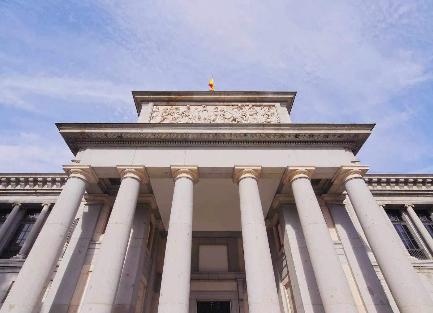 Stone columns, sculpted pediment, and Spanish flag at the Prado Museum in Madrid