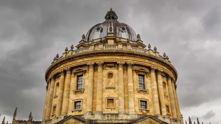 The stone facade and domed roof of the Radcliffe Camera in Oxford under a cloudy sky