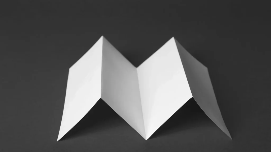 A white sheet with parallel zigzag folds standing against a dark gray background