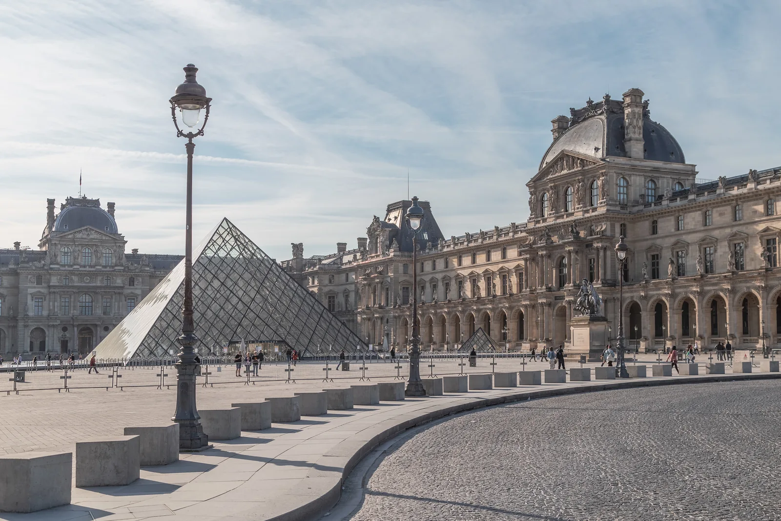 The glass Louvre Pyramid stands in the museum courtyard beside the palace buildings.