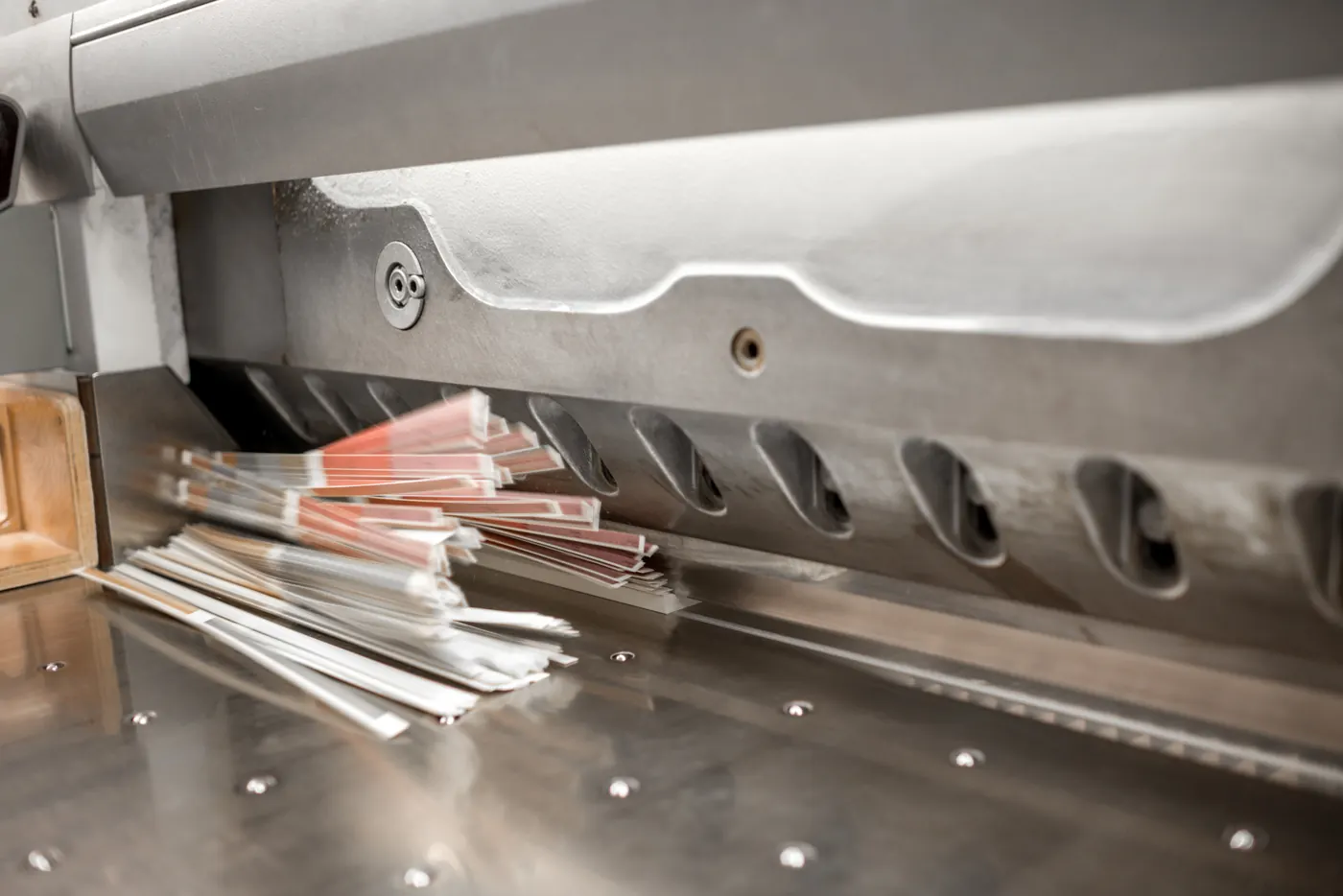 Close view of a commercial paper cutter and stacked printed sheets.