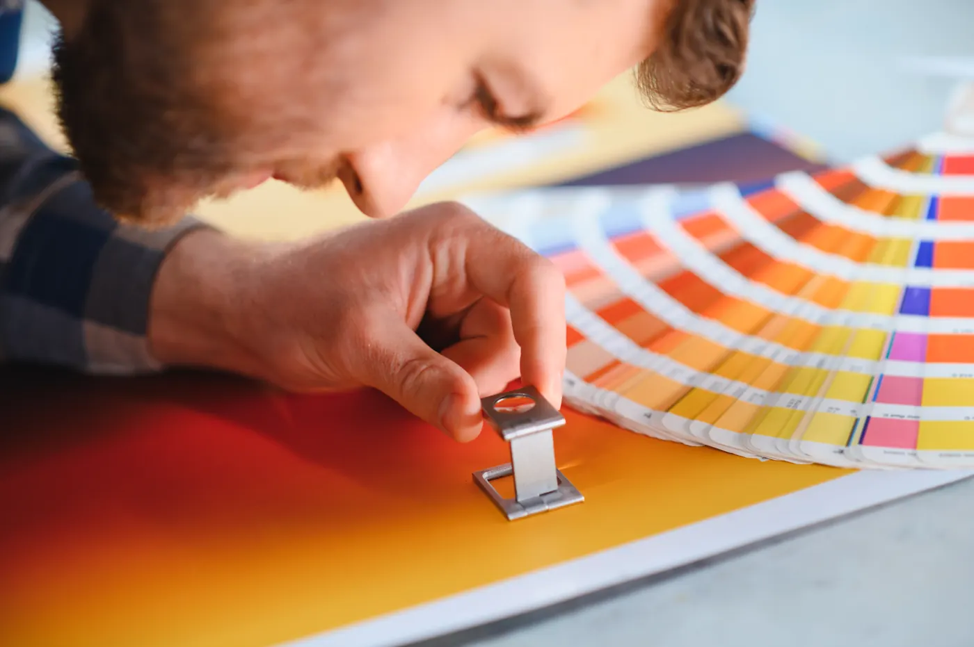 A person looking through a magnifying loupe at a printed color sample.