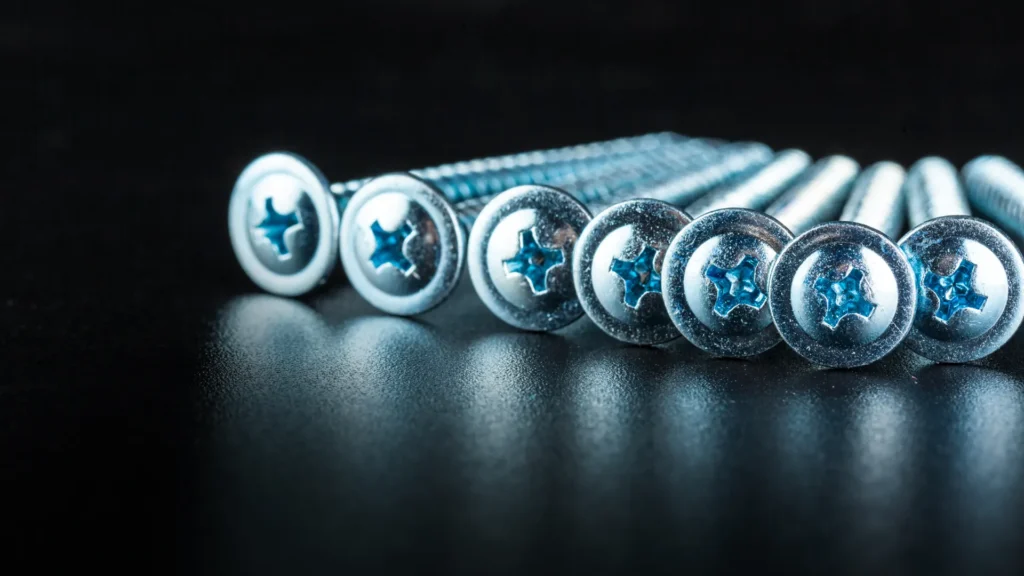Silver cross-recess screw heads arranged on a dark surface