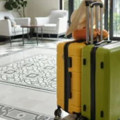 Two upright suitcases with a sun hat in a bright hotel lobby.