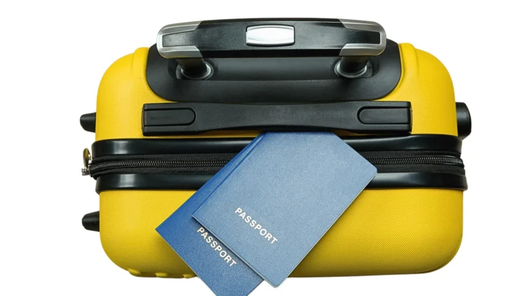 Two closed passports resting on a yellow suitcase against a white background.