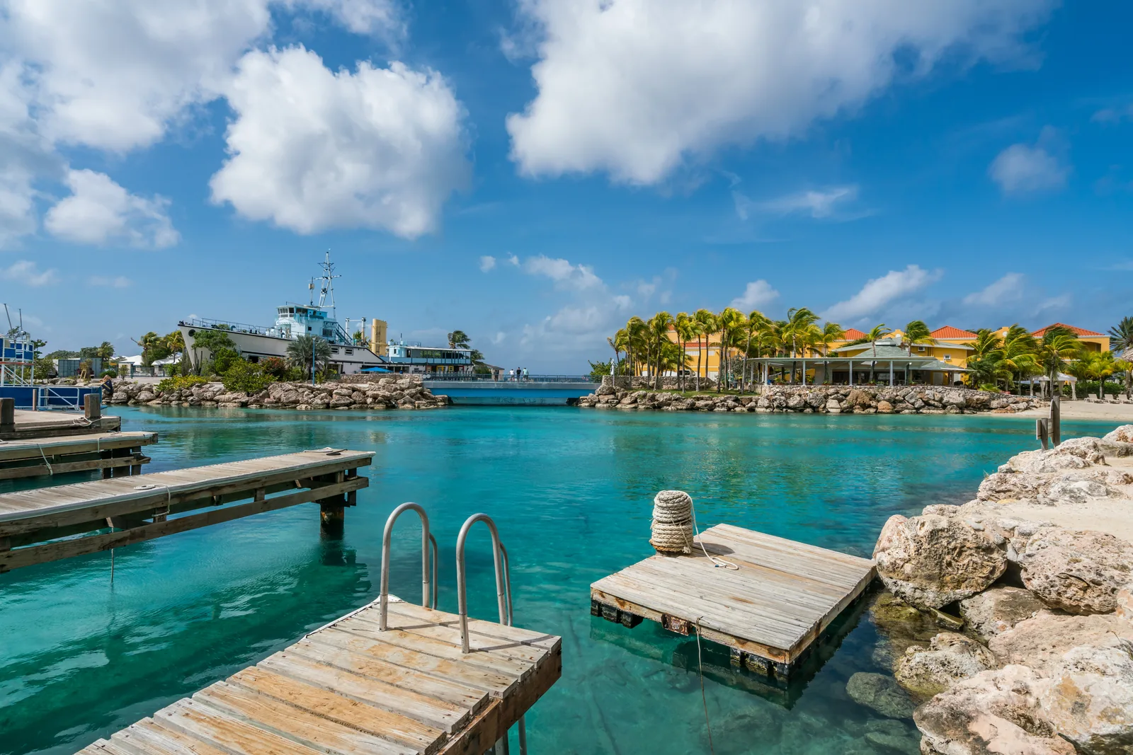 A pier extends over clear turquoise water beneath a blue sky.