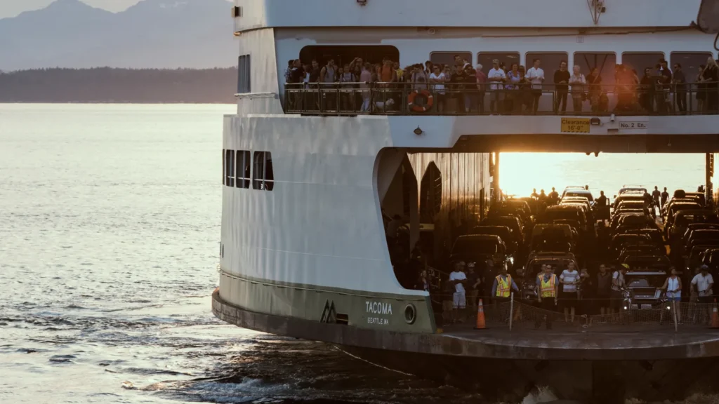 The Tacoma ferry carrying cars on its vehicle deck and people on upper decks in golden evening light