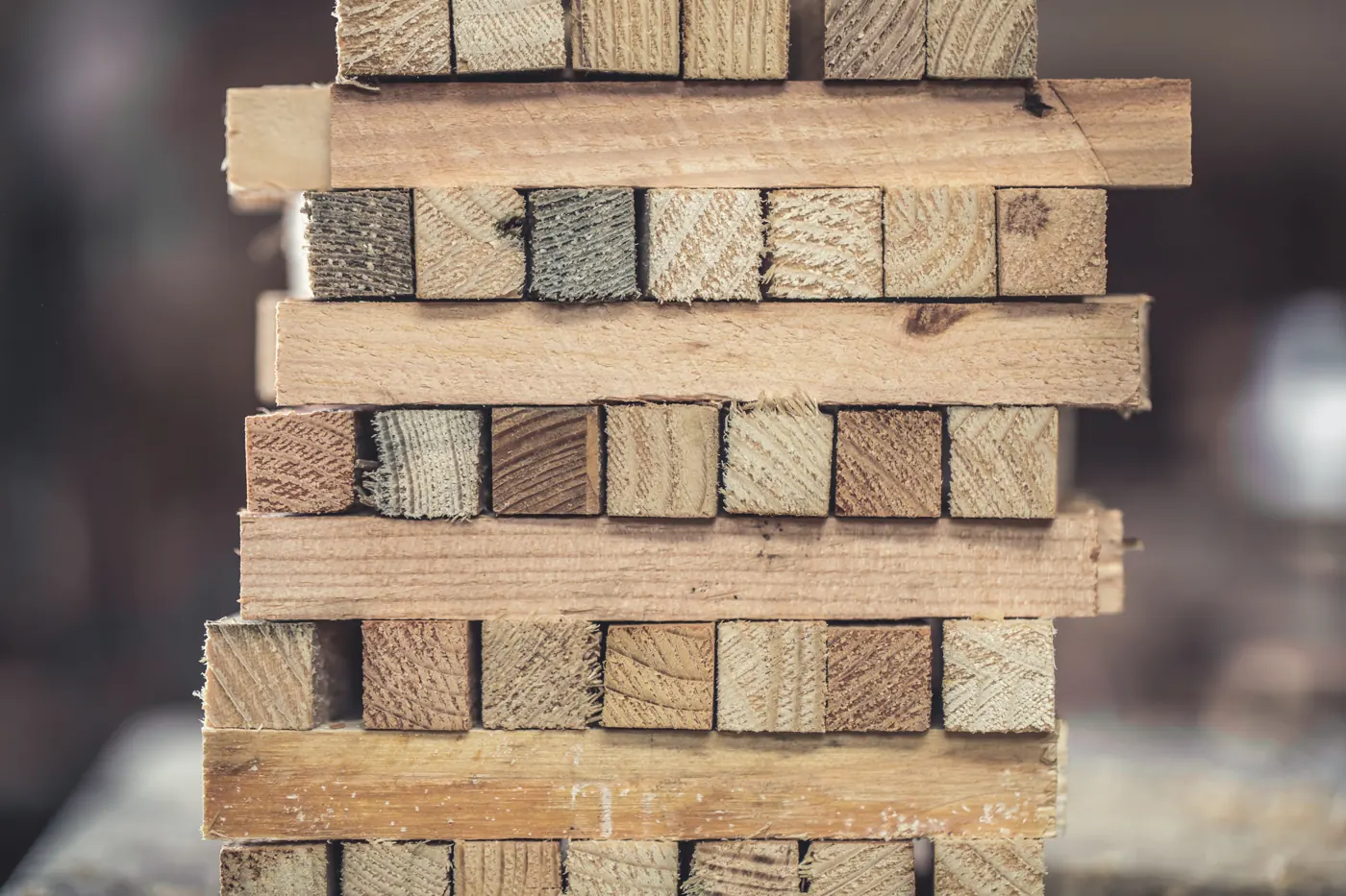 The ends of rectangular wood pieces are stacked in alternating layers.